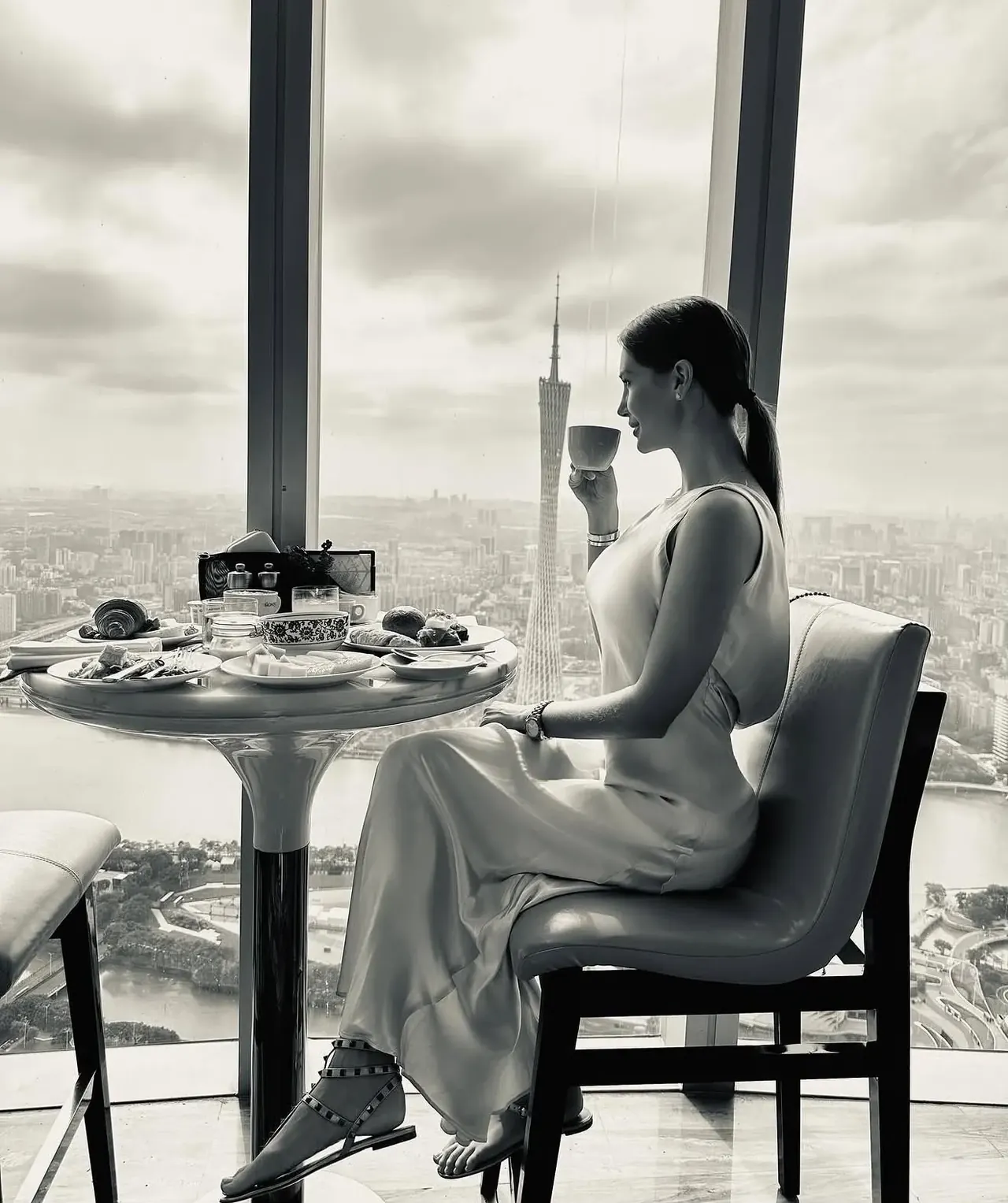 Giovanna no café da manhã do Rosewood Guangzhou, com a Canton Tower na janela, em preto e branco